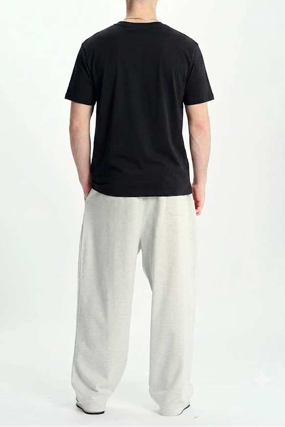 A man viewed from behind wearing a plain black short-sleeve t-shirt and light gray wide-leg sweatpants against a white studio background.