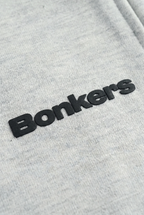 Close-up of a light heather gray fabric with a black 3D embroidered 'Bonkers' logo.